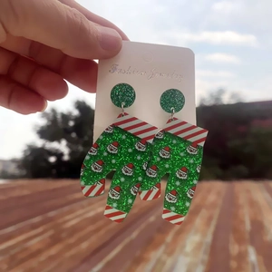 Close-up of green glitter Christmas earring with Santa Claus print on card display