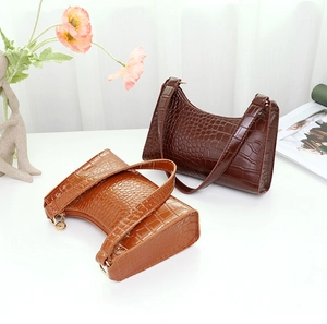 Detail shot of crocodile pattern shoulder bags in dark coffee and brown on a styled table
