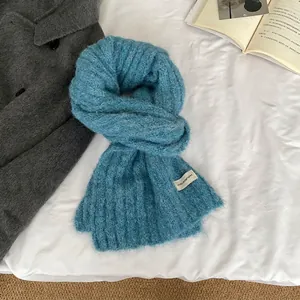 Detail of soft blue knitted wool scarf with premium brand tag on cozy bedding