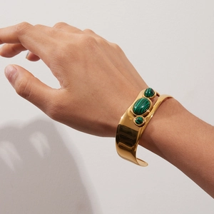 Close-up of a gold stainless steel open bangle inlaid with three green malachite stones