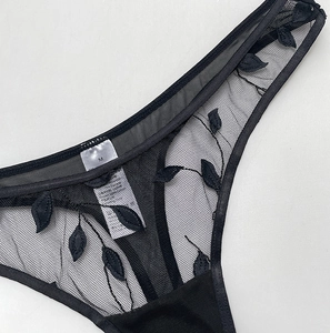Detailed close-up of black mesh panties featuring intricate leaf embroidery and sheer texture