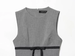 Detail of grey sleeveless dress featuring a satin black bow and waist ribbon