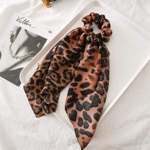 Detailed view of leopard print satin scrunchie with long ribbons on a white tray