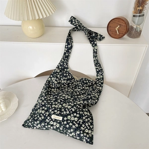 Detail of floral canvas tote bag featuring an adjustable bow shoulder strap and daisy print