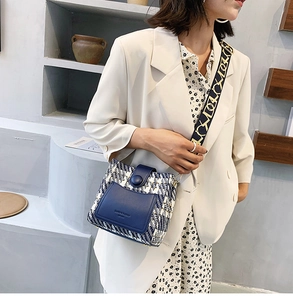 Detail of blue and white woven crossbody bucket bag with textured leather and wide strap