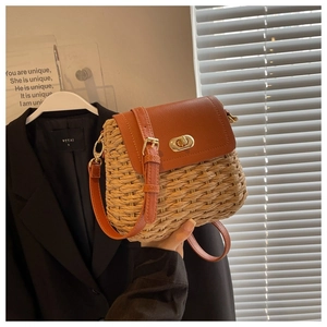 Close-up of woven straw handbag with orange-brown leather texture and metal swivel clasp