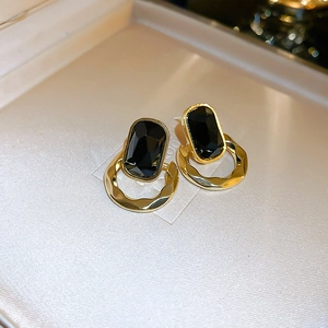 Makroaufnahme langer schwarzer Edelsteinohrringe mit goldenen Fransen im Vintage-Stil