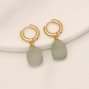 Macro detail of gold cross charm on light green natural stone earring with metal loop