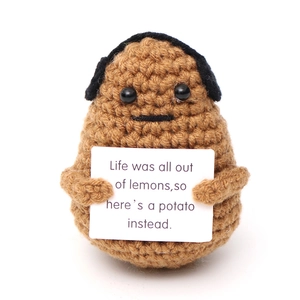 Detail of handmade crochet potato plush holding a sign with inspirational English text