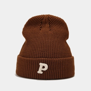 Detail view of brown knit beanie featuring a white P letter embroidery and thick texture