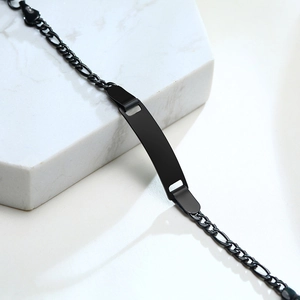 Macro detail of black stainless steel Figaro chain and blank ID plate for kids on marble