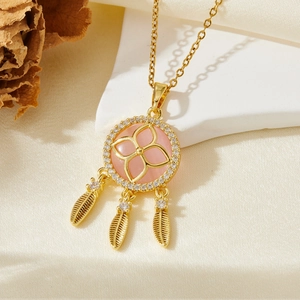 Détail d'un collier attrape-rêves doré avec pierre rose et pendentifs en plumes