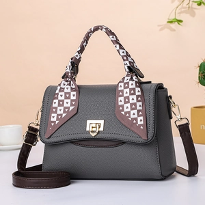 Close-up of lychee-textured dark grey handbag with a decorative silk scarf on handle