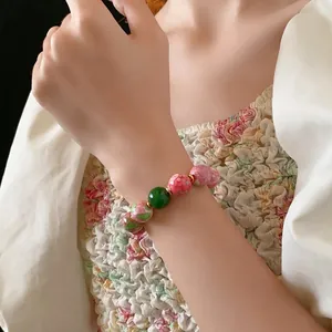 Gold plated beaded ceramic bracelet with floral patterns and a green focal bead for women