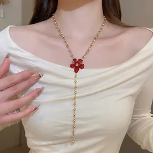 Elegant long gold bead chain necklace with a large red flower pendant and tassel