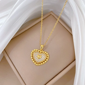Golden heart pendant necklace with shimmering crystals on a beige leather jewelry box