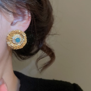 Macro shot of vintage gold flower earring with turquoise stone and zircon accents