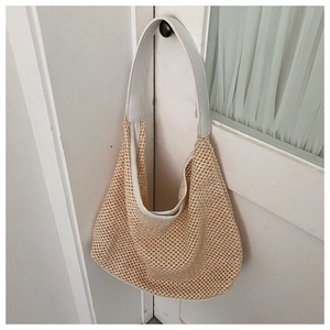 Detail of hollow-out mesh straw texture and white strap on the woven shoulder bag