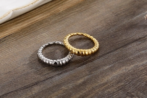 Detailed view of gold and silver croissant dome rings on a dark wood texture surface