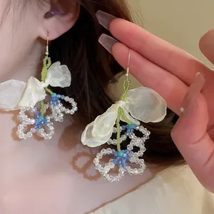 Detail of beaded floral tassel earrings with chiffon petals and green beaded stems