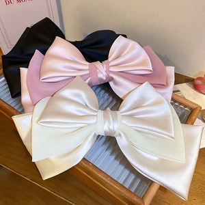 Detail of oversized satin and chiffon bow hair clips in black, pink and beige