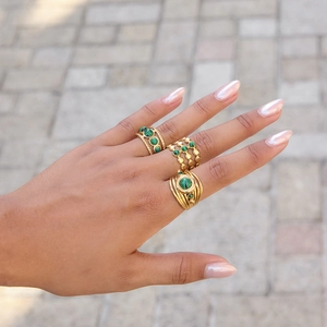 Golden multi-layer hollow open rings with green malachite stones on model's hand
