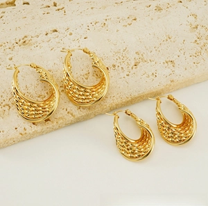 Detailed close-up of gold-plated woven texture earrings on a natural stone base