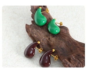 Detail of vintage teardrop earrings with green and brown enamel on rustic wood background