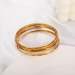 Macro shot of layered gold bracelets featuring hammered texture and a metallic finish
