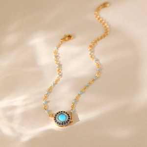 Bohemian gold chain bracelet with turquoise pendant and blue beads on beige background