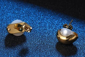 Détails de boucles d'oreilles créoles dorées avec perles semi-circulaires et fermoirs papillon