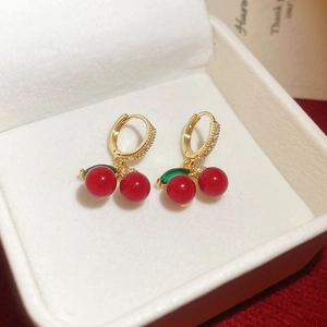 Detail shot of cherry earrings with red stones and gold cubic zirconia in a jewelry box