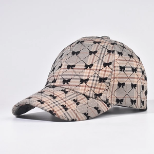 Detail view of plaid baseball cap with black bow print and curved brim texture