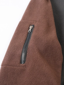 Close-up of brown fleece jacket fabric with vertical zipper pocket detail and metal slider