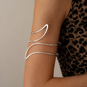 Detailed view of a silver wave arm cuff on upper arm with a stylish leopard dress