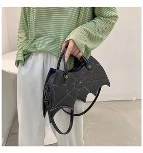 Detail of bat-shaped gothic handbag showing white spider web stitching and silver cross