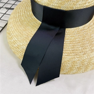 Close-up of a woven straw sun hat with detailed black ribbon and natural texture