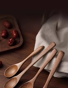 Close-up of four natural wenge wood spoons with unique grain on a rustic tray