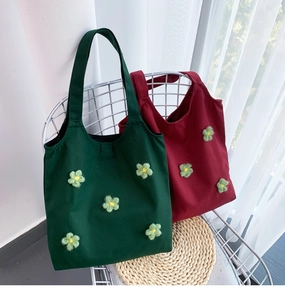 Close-up of canvas tote bag with 3D handmade floral decorations on white iron chair