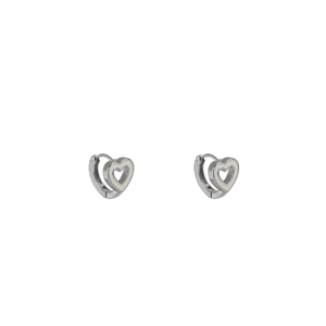 Vue macro des boucles d'oreilles cœur argentées avec incrustation émail blanc poli