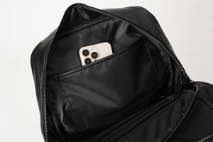 Interior view of black woven backpack showing inner pocket with a smartphone for scale