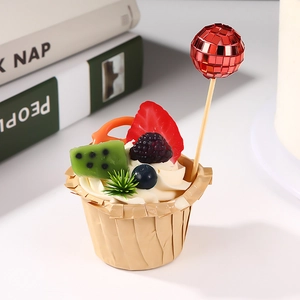 Close-up of a cupcake with fresh fruit and a reflective red disco ball topper for parties
