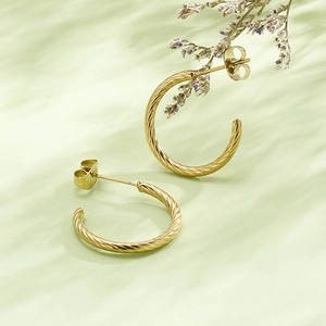 Macro view of gold twisted C-shape earrings featuring a textured rope design