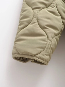 Detailed close-up of quilted pattern and cuff stitching on the khaki padded jacket