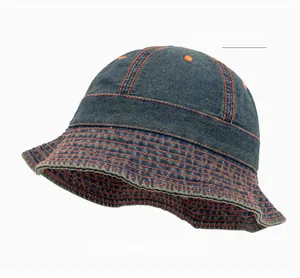 Détail d'un bob en denim bleu foncé avec surpiqûres orange contrastées et œillets d'aération