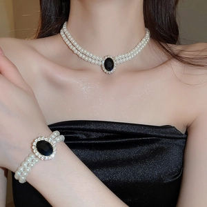 Close-up of double-layer pearl necklace with a black oval pendant and sparkling crystals