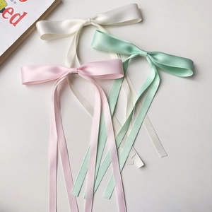Satin ribbon bow clips in white, pink and green shown in a detailed flat lay view