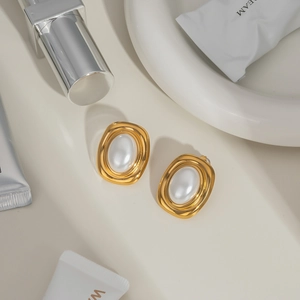 Detailed close-up of retro gold-plated earrings with large white pearl insets