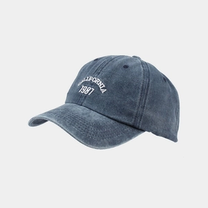 Detail of embroidered CALIFORNIA 1987 text on washed blue denim baseball cap