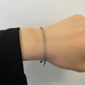 Rainbow tennis bracelet featuring colorful gemstones in a silver-plated setting on a wrist